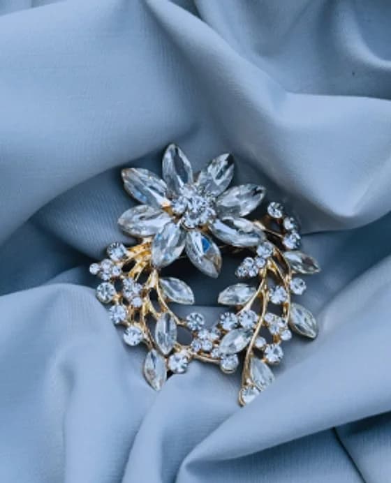 Crystal wreath brooch in a gold-tone setting on blue fabric